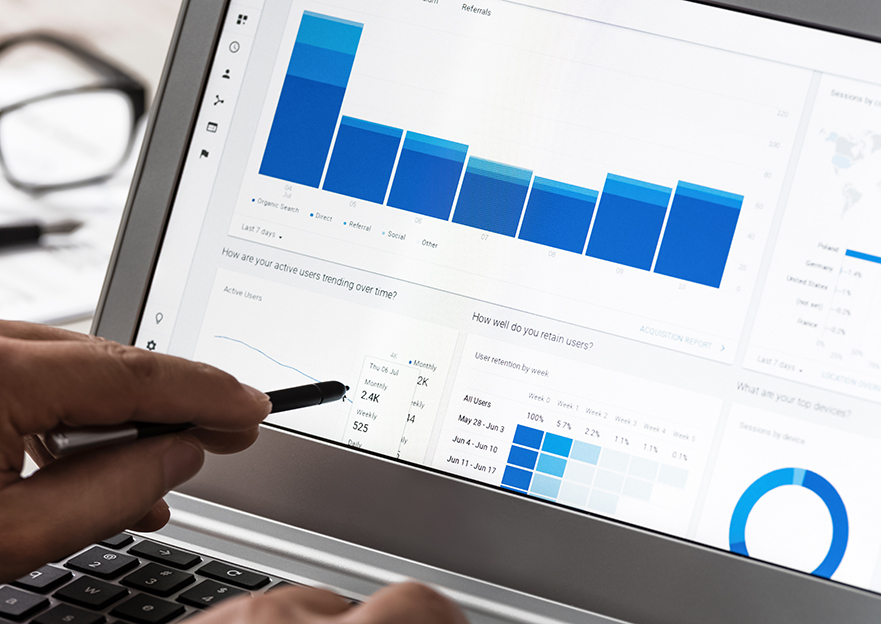 Photograph of a macbook with a Google Analytics showing charts and website data.