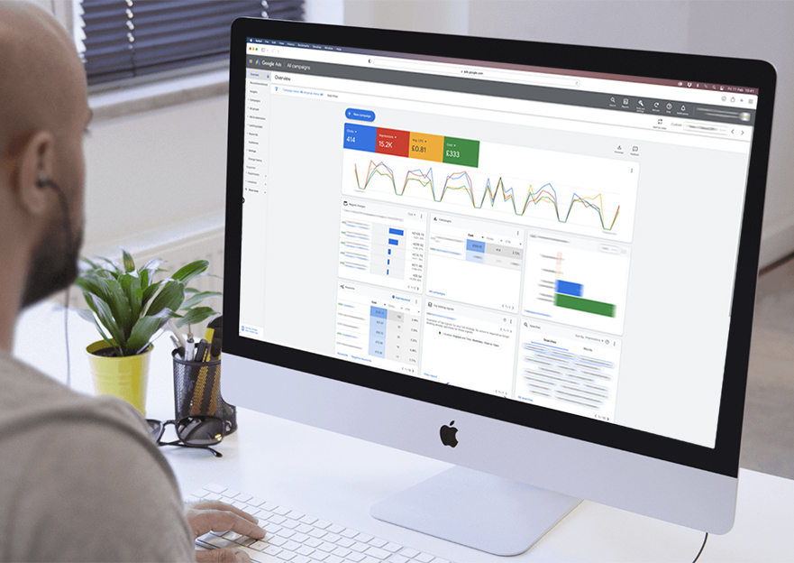 Photograph of a man looking at an imac display a Google Ads campaign