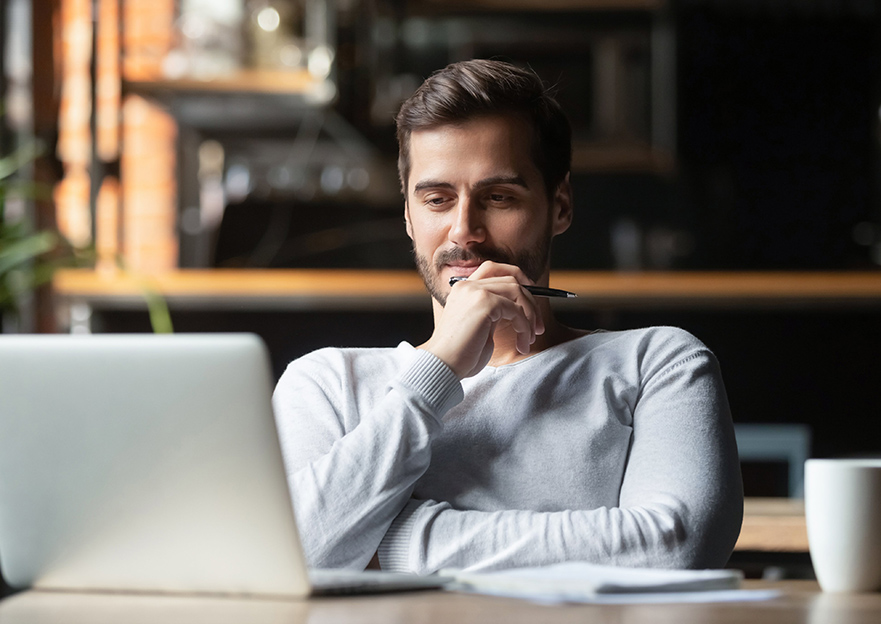 Photograph of a man thinking at a desk with a macbook